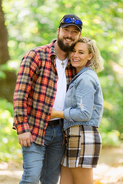 Smiling couple posing among fall leaves