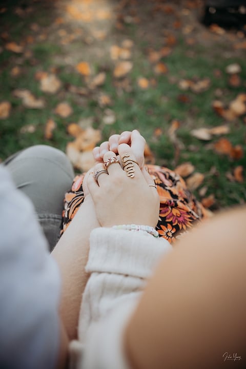 Close-up of a couple holding hands over fallen leaves