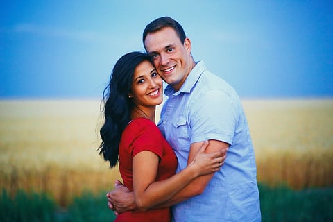 Couple embracing in a golden wheat field at sunset