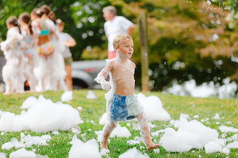 Boy running through foam on the grass