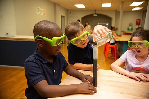 Kids in safety goggles doing a science experiment