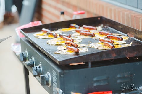Hot dogs sizzling on a griddle at a cookout