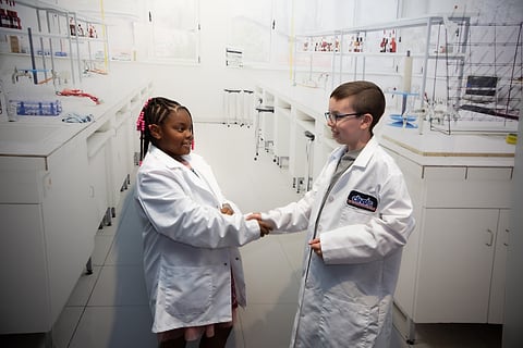 Young scientists in lab coats shaking hands