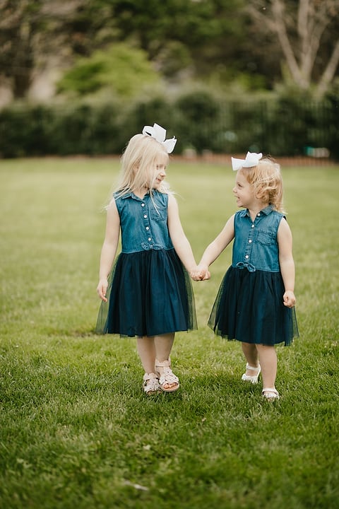 Two little sisters holding hands in matching dresses