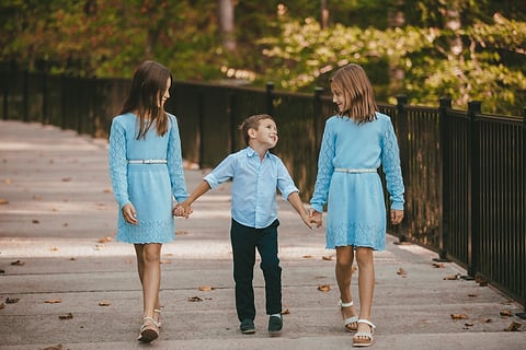 Three siblings walking together on a boardwalk