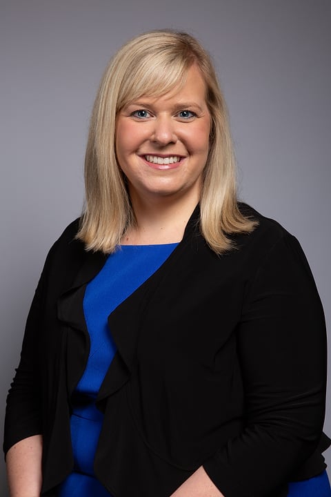 Business headshot of a smiling woman in a blazer