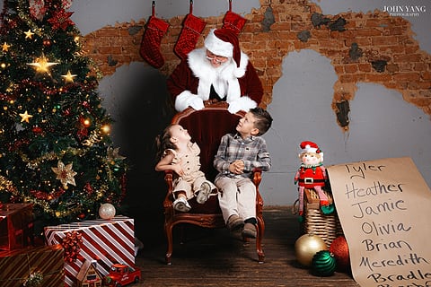 Two children visiting Santa by the Christmas tree