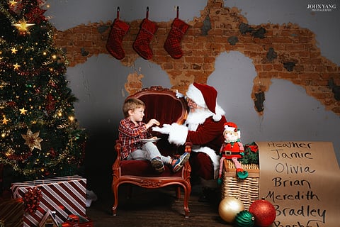 Boy sitting with Santa in a holiday studio set