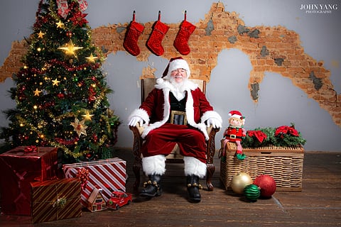 Santa seated beside the Christmas tree