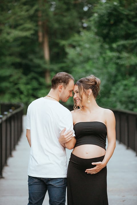Couple touching foreheads on a wooded bridge
