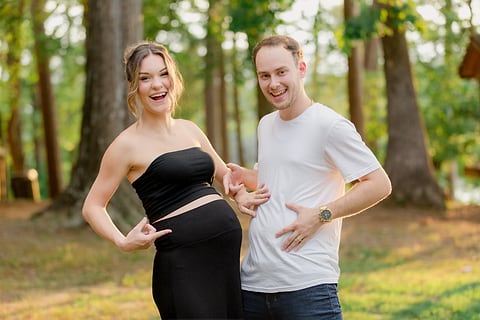 Joyful expecting couple pointing to the baby bump