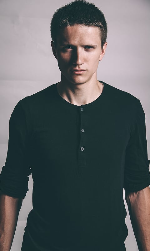 Model in a black henley on a light backdrop