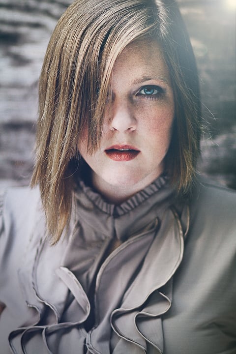 Model with side-swept hair in a ruffled blouse