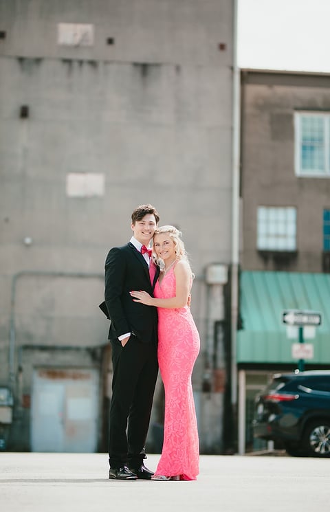 Prom couple posing in front of brick buildings