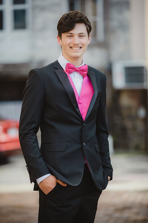 Prom portrait of a young man in a tuxedo with a pink bow tie
