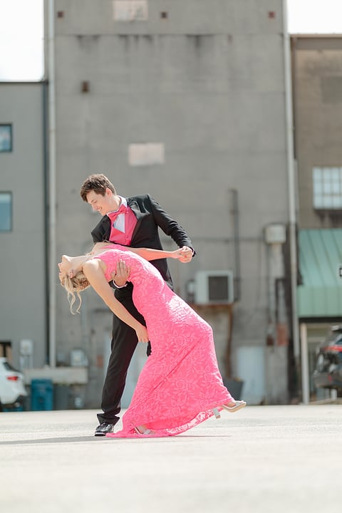 Prom couple doing a dramatic dip on the street