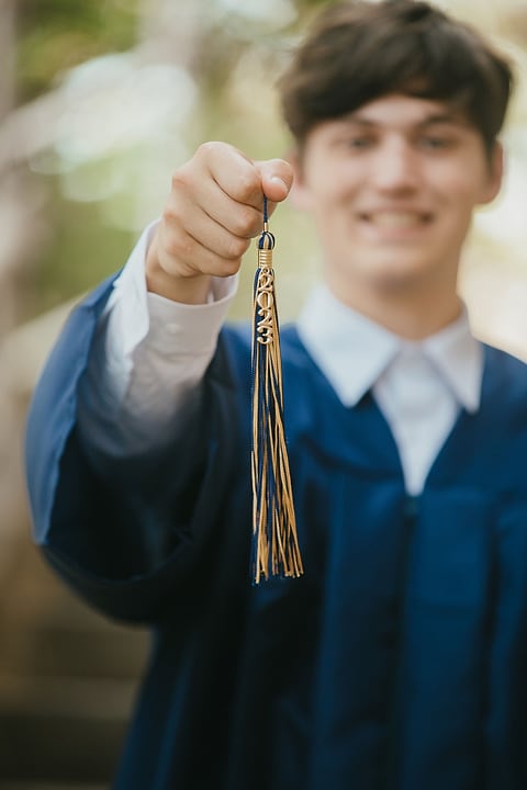 Graduate holding his tassel toward the camera